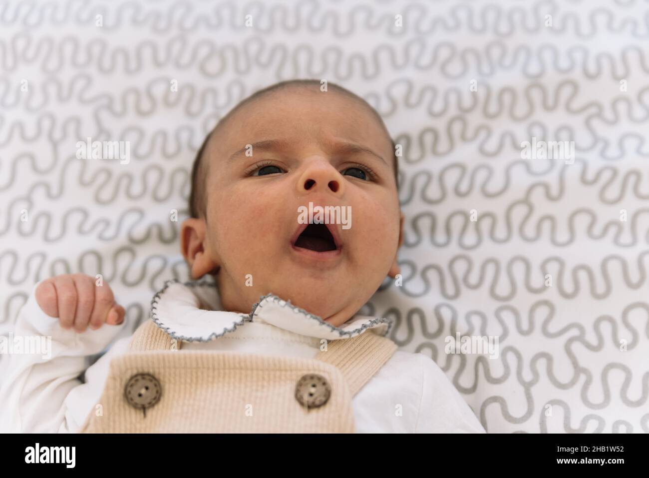 Bébé élégant en costume et salopette couchée sur le lit. Banque D'Images