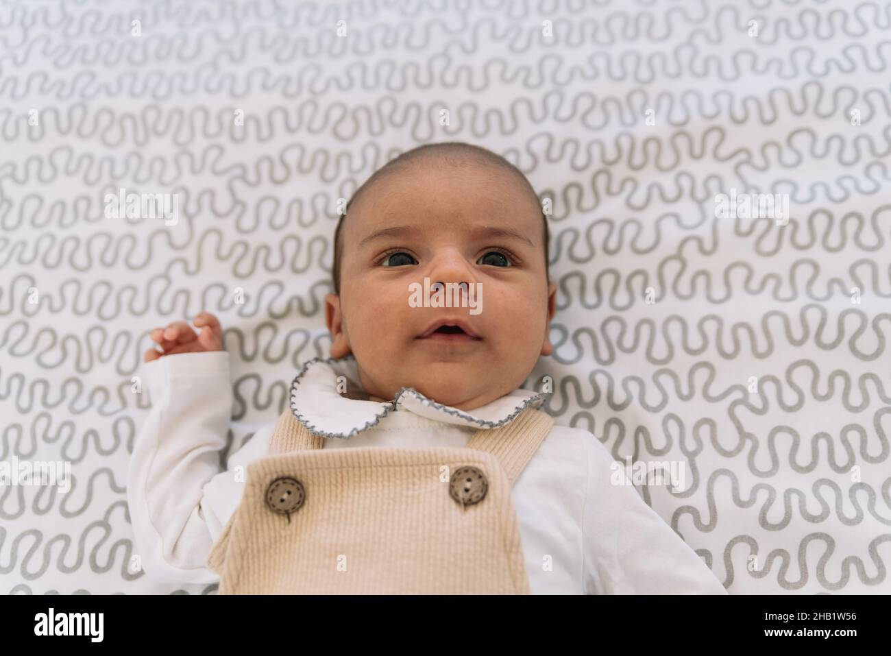 Bébé élégant en costume et salopette couchée sur le lit. Banque D'Images
