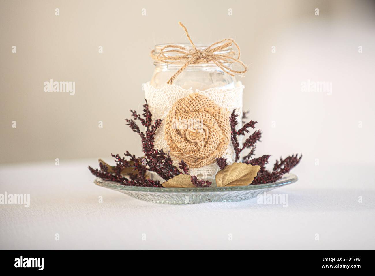 Porte-bougie en verre recouvert de dentelle avec décoration en toile de jute sur surface blanche Banque D'Images