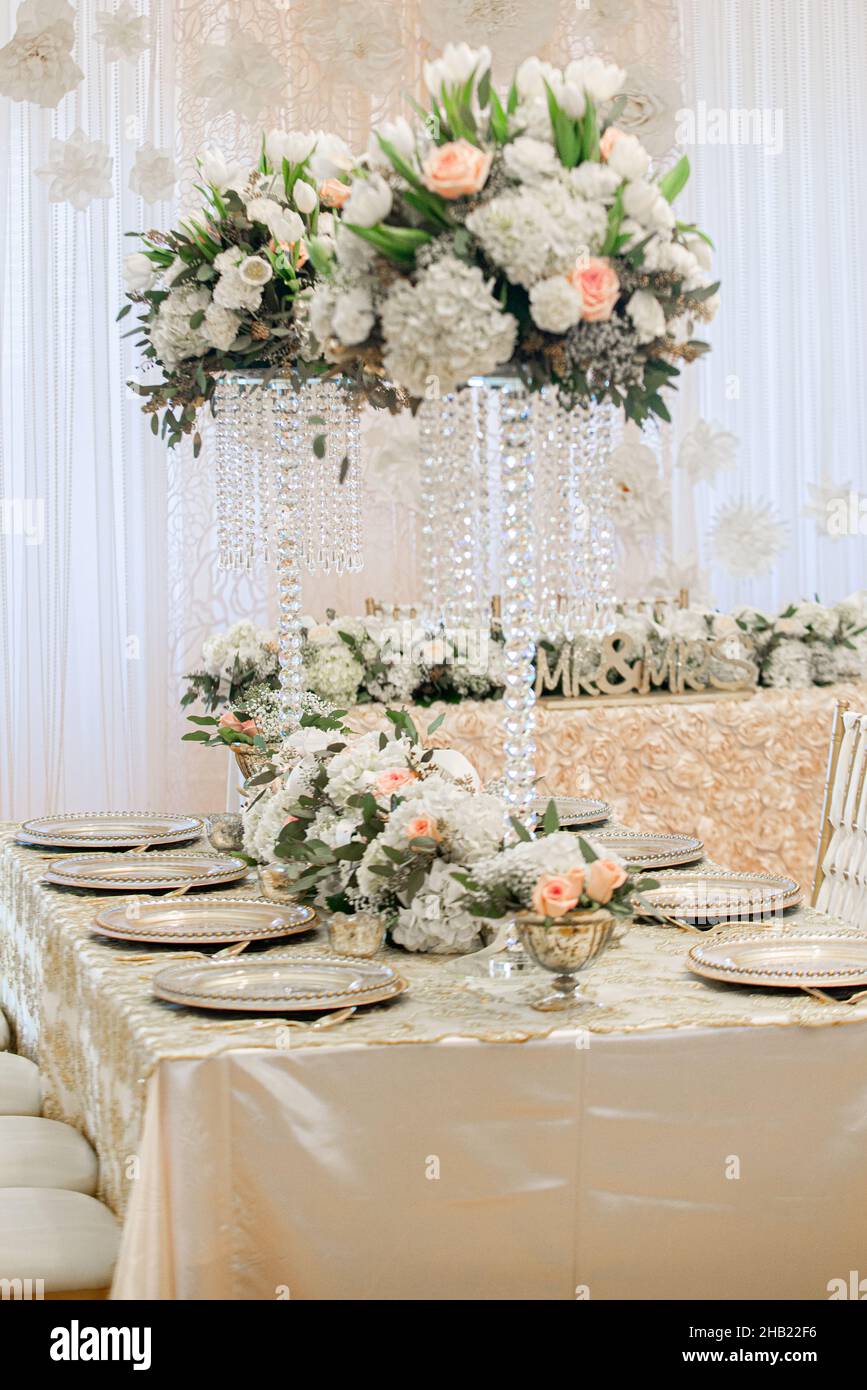 Magnifique paysage de table rempli de plaques de chargement dorées, de fleurs et de vases en cristal à la réception de mariage Banque D'Images