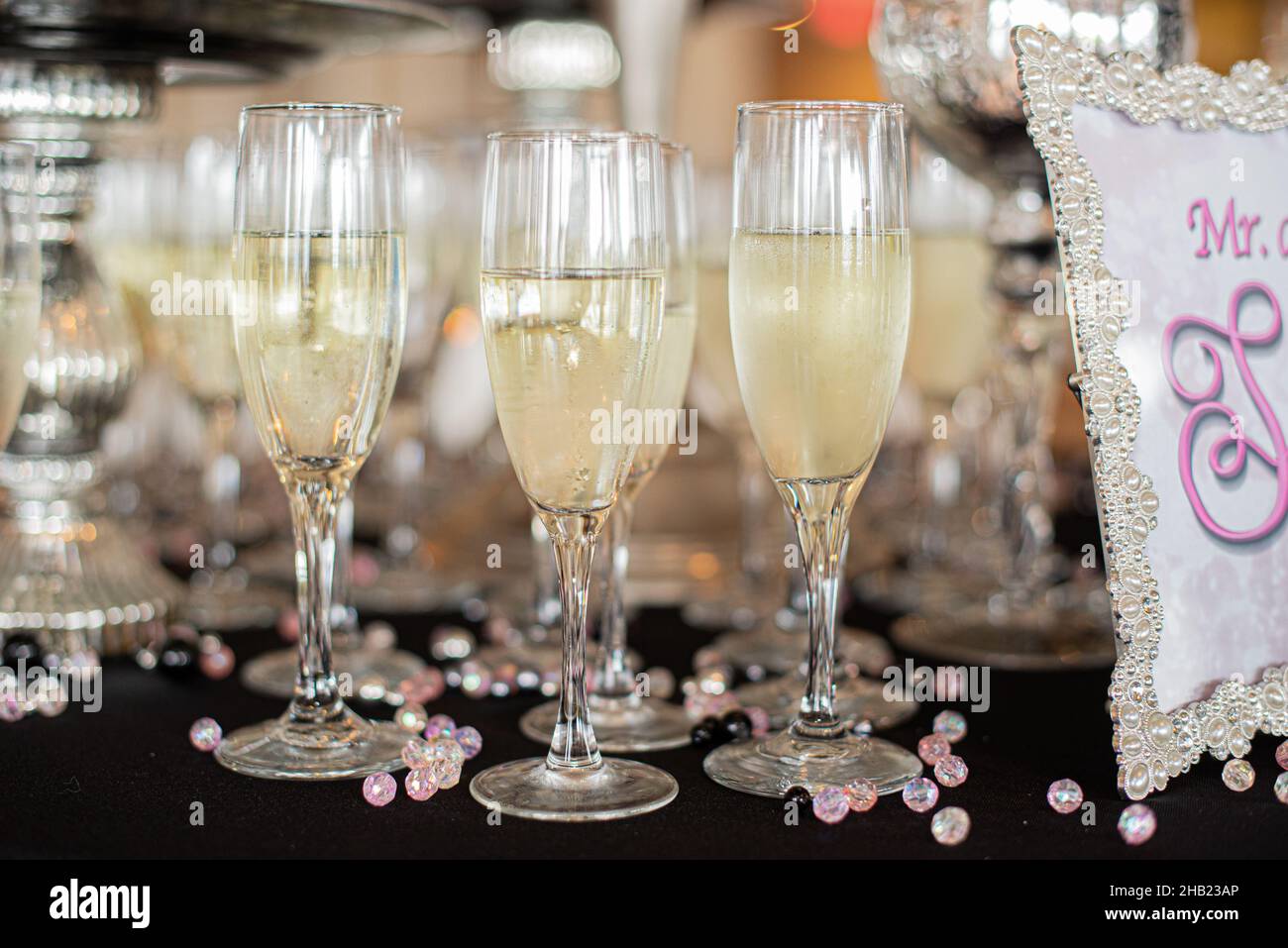 Des verres remplis de champagne, prêts à servir lors de la réception de mariage, assortis de perles roses, sont prêts à servir lors de la réception de mariage Banque D'Images