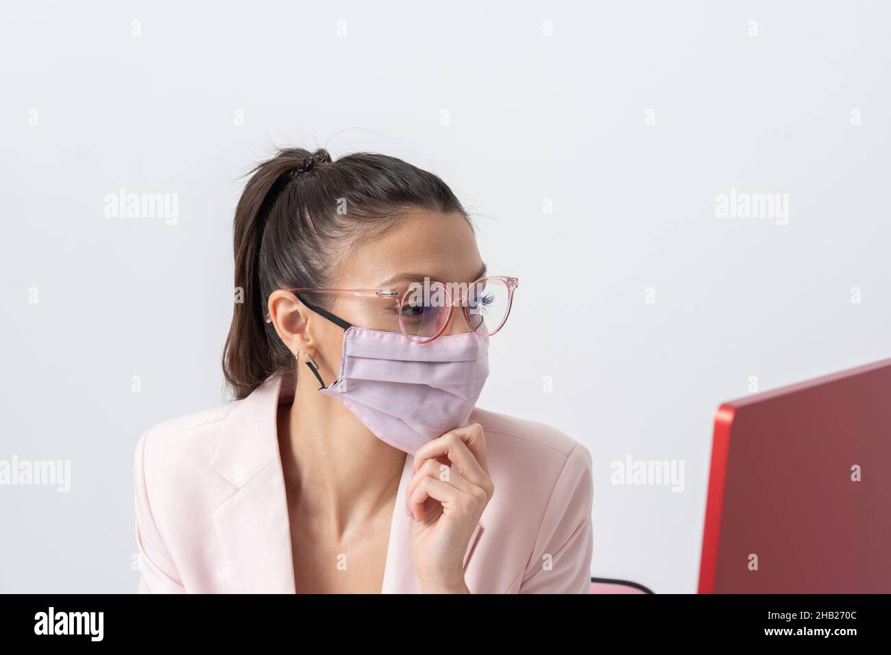 Salisbury, Wiltshire, Royaume-Uni.2021. Femme attrayante portant un masque rose et utilisant un ordinateur et un clavier. Banque D'Images