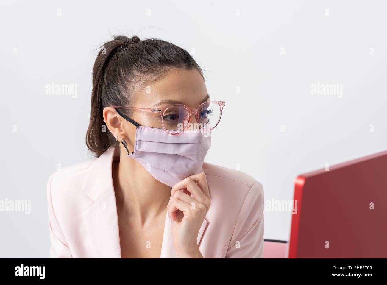 Salisbury, Wiltshire, Royaume-Uni.2021. Femme attrayante portant un masque rose et utilisant un ordinateur et un clavier. Banque D'Images