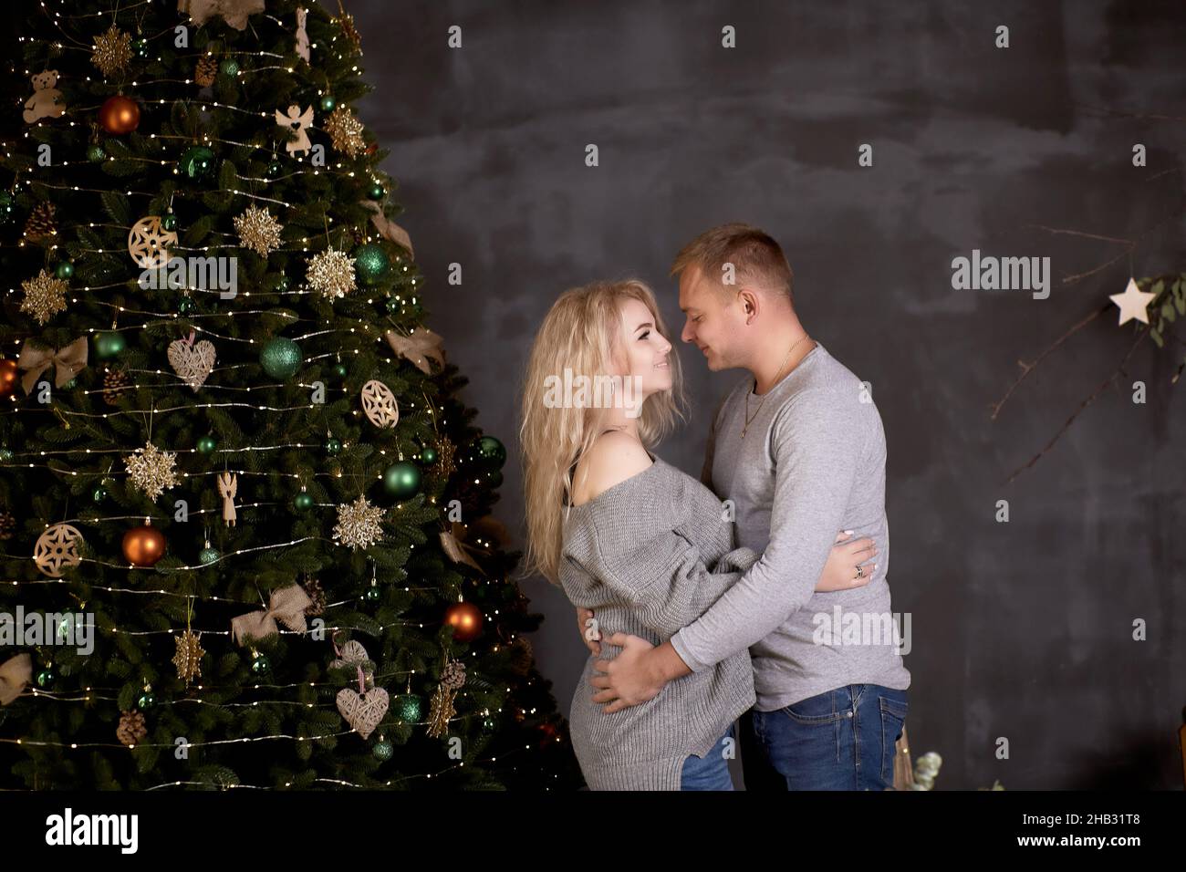 Couple épris d'homme et de femme blonde dans l'esthétique intérieure confortable avec arbre de Noël festif.Le vrai moment, franc.Bonne humeur et s'amuser Banque D'Images