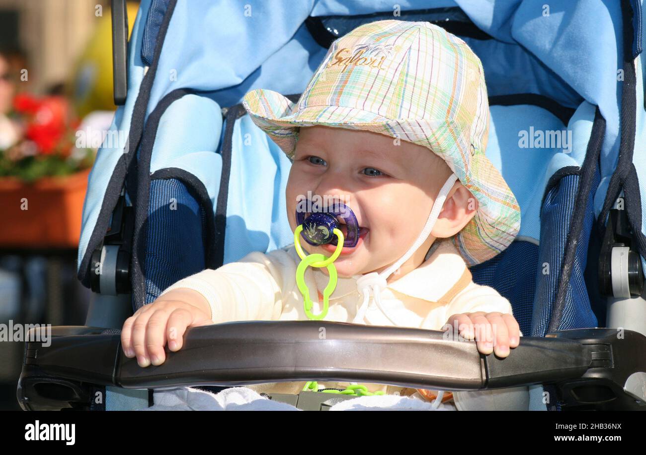 Bébé garçon d'un an avec sucette regardant de sa poussette et sourires  Photo Stock - Alamy