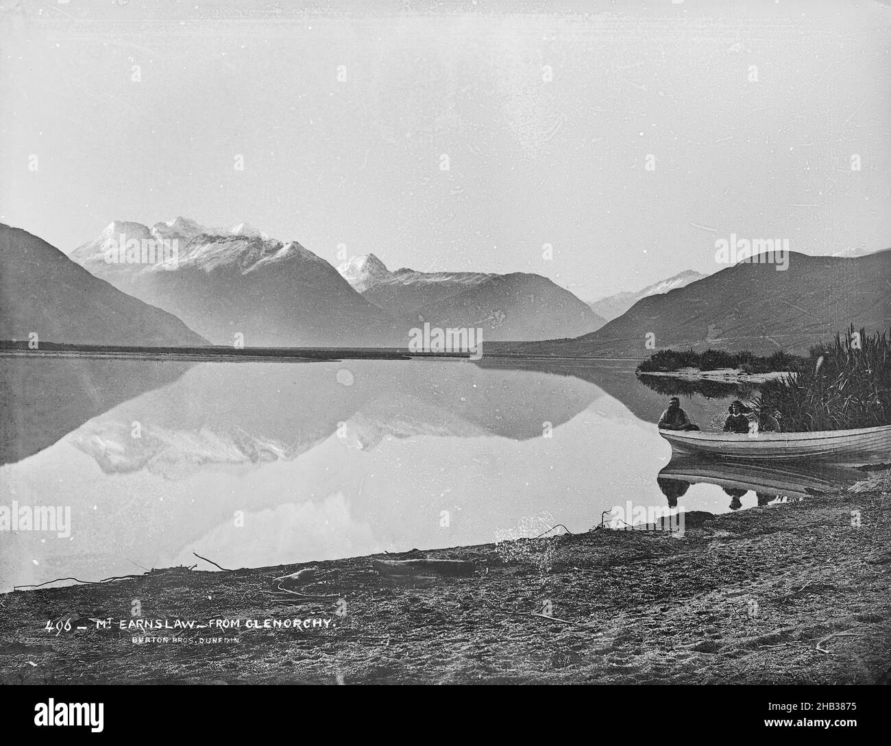 Mt Earnslaw, de Glenorchy, studio Burton Brothers, studio de photographie, Nouvelle-Zélande,Photographie en noir et blanc, vue sur un lac aux montagnes enneigées.Canot avec deux personnes à droite Banque D'Images