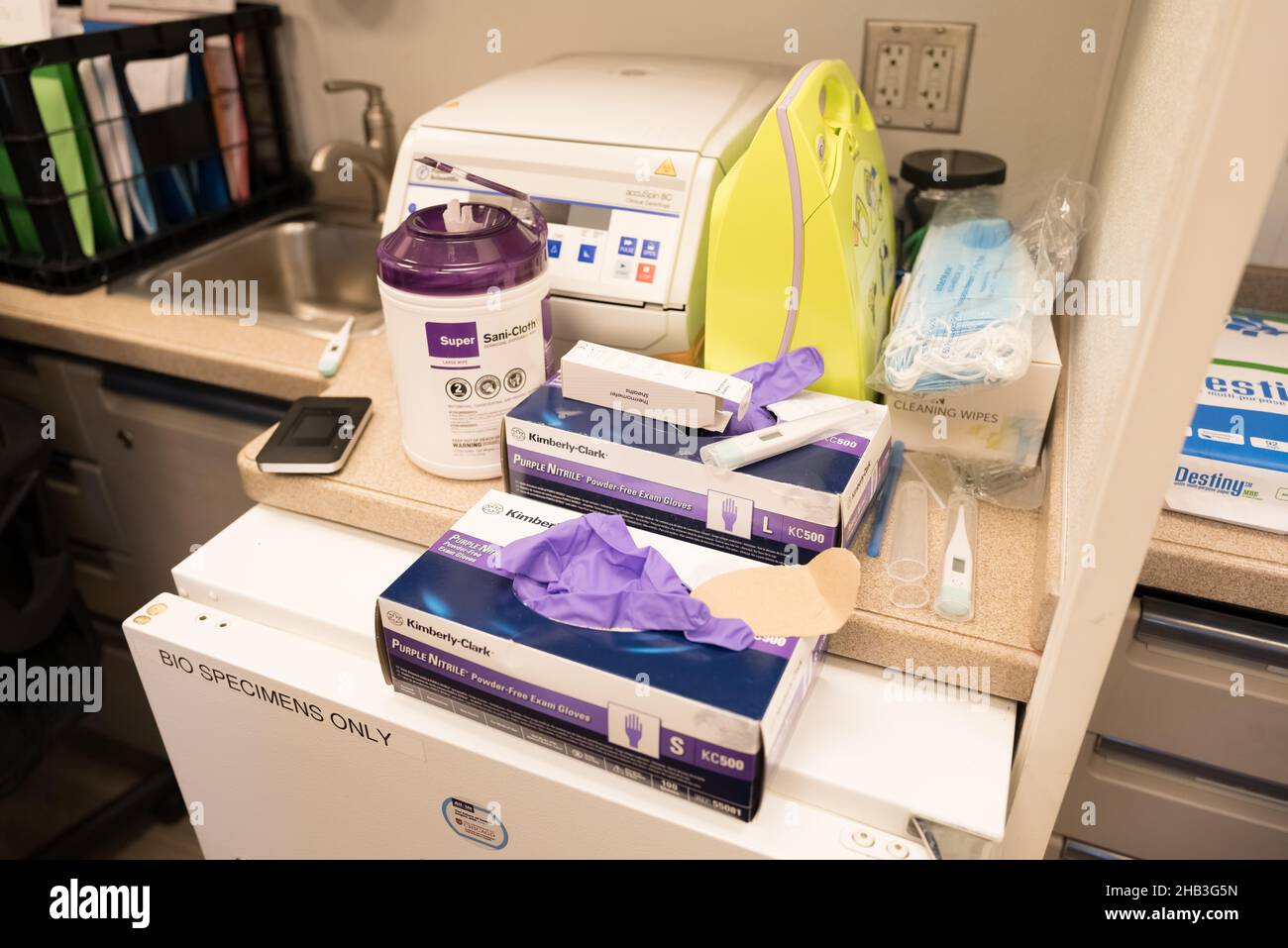 Espace de laboratoire avec des boîtes de gants jetables Kimberly-Clark violettes, posés au-dessus d'un réfrigérateur pour échantillons biologiques. Banque D'Images