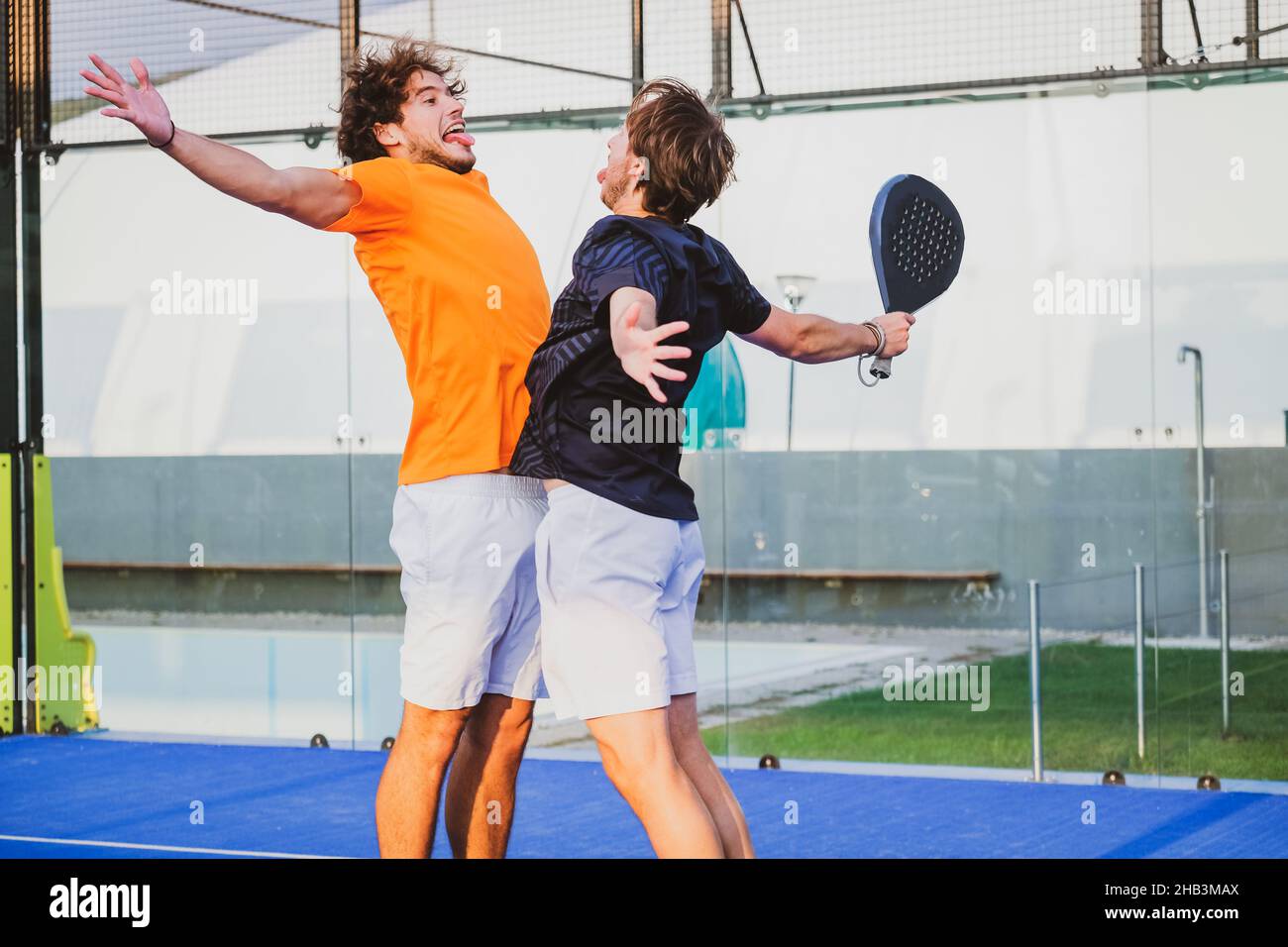 Portrait de deux sportifs souriants posant sur un terrain de padel en plein air avec des raquettes - les joueurs de padel embrassant après avoir gagné un match de padel Banque D'Images