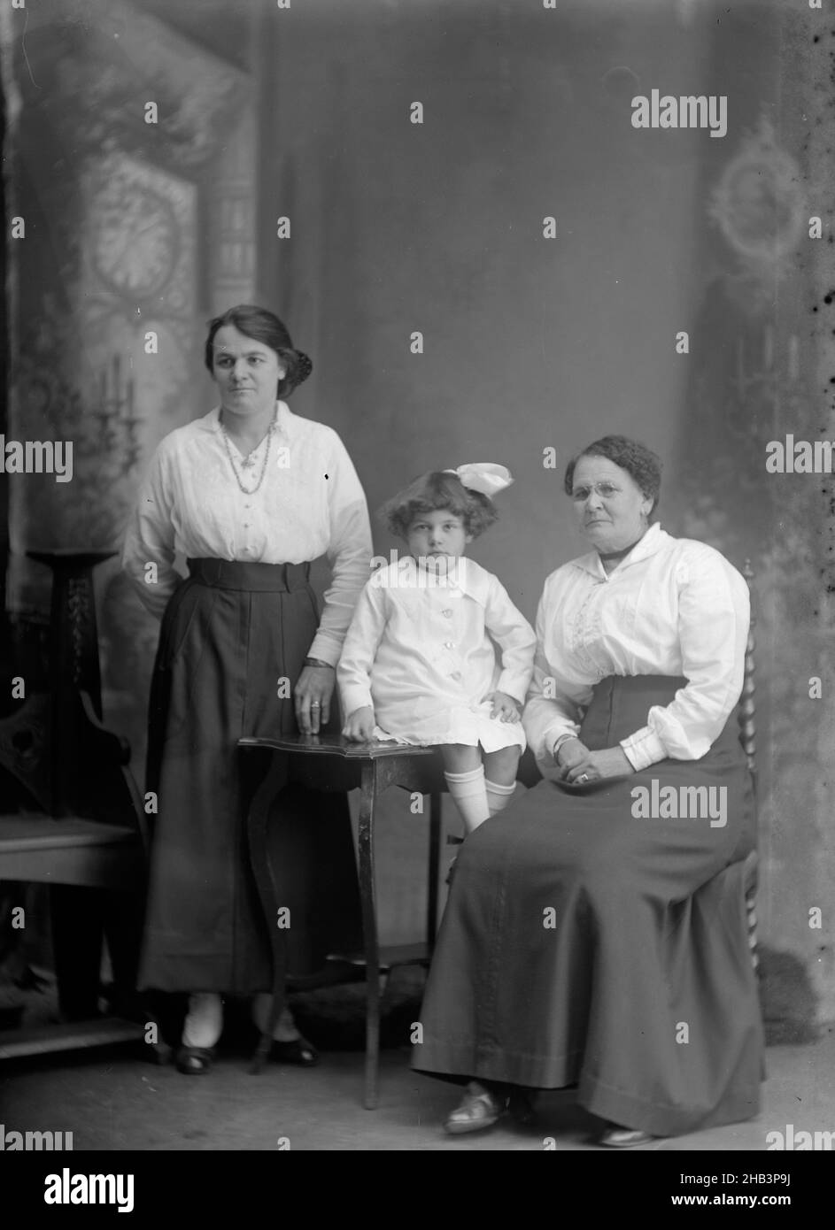 Flanigan 6 BKK CAB, Berry & Co, vers 1920, Wellington, deux femmes,une assise et une debout, et une petite fille assise sur une table Banque D'Images