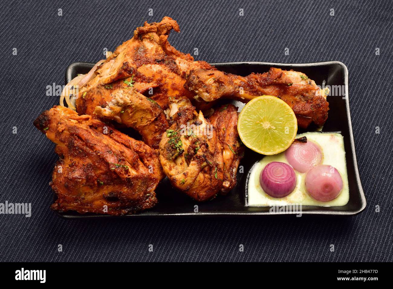 Poulet Tandoori avec chutney, citron et oignon dans une assiette Banque D'Images