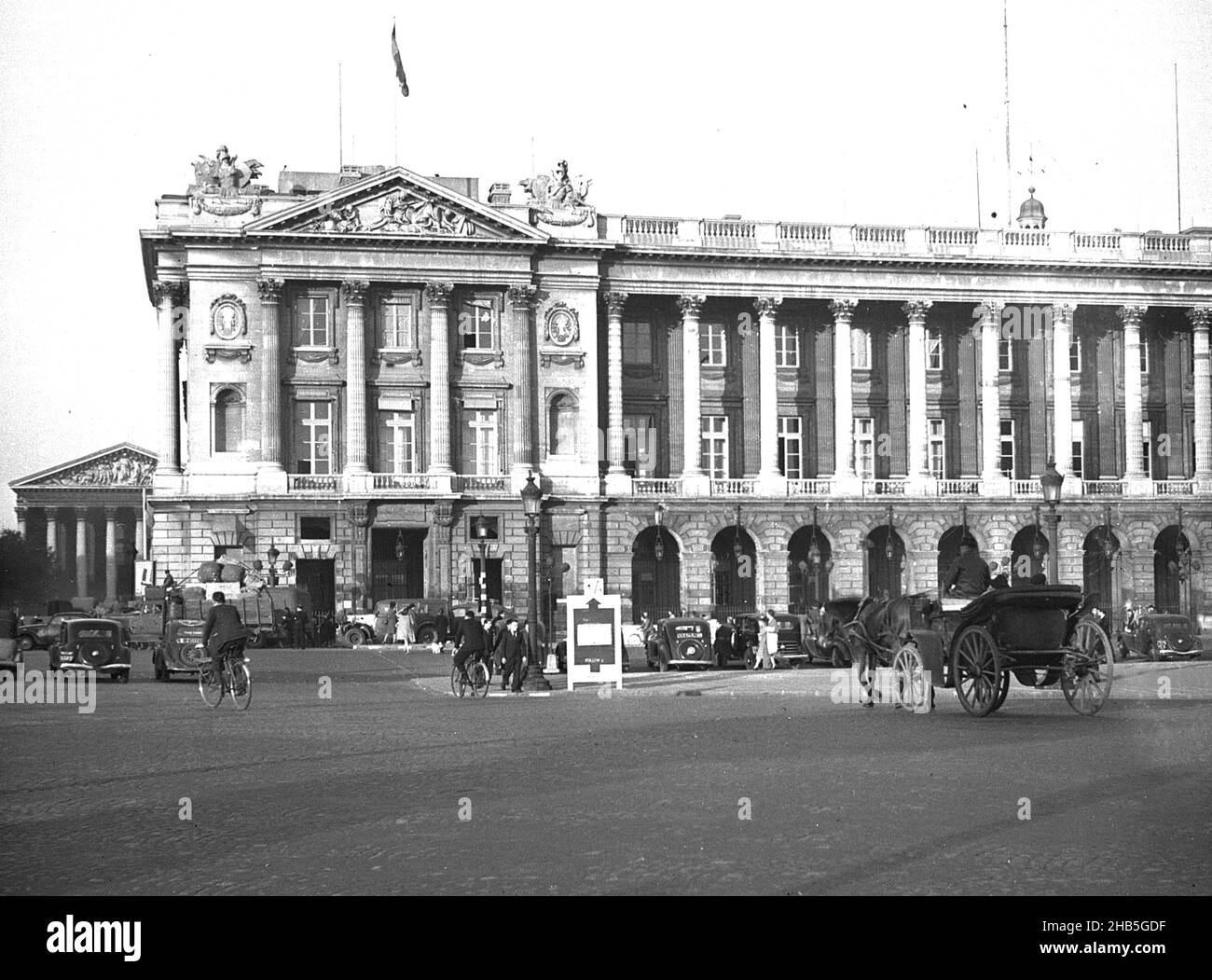 Place de la Concorde avec véhicules et piétons, 1945.Une photo du soir de printemps, prise alors que la guerre en Europe s'achève, représente l'Hôtel de la Marine et un peu de la Madeleine sur le fond arrière gauche.On y trouve une variété d'automobiles, de cyclistes, de calèche et de piétons. Banque D'Images