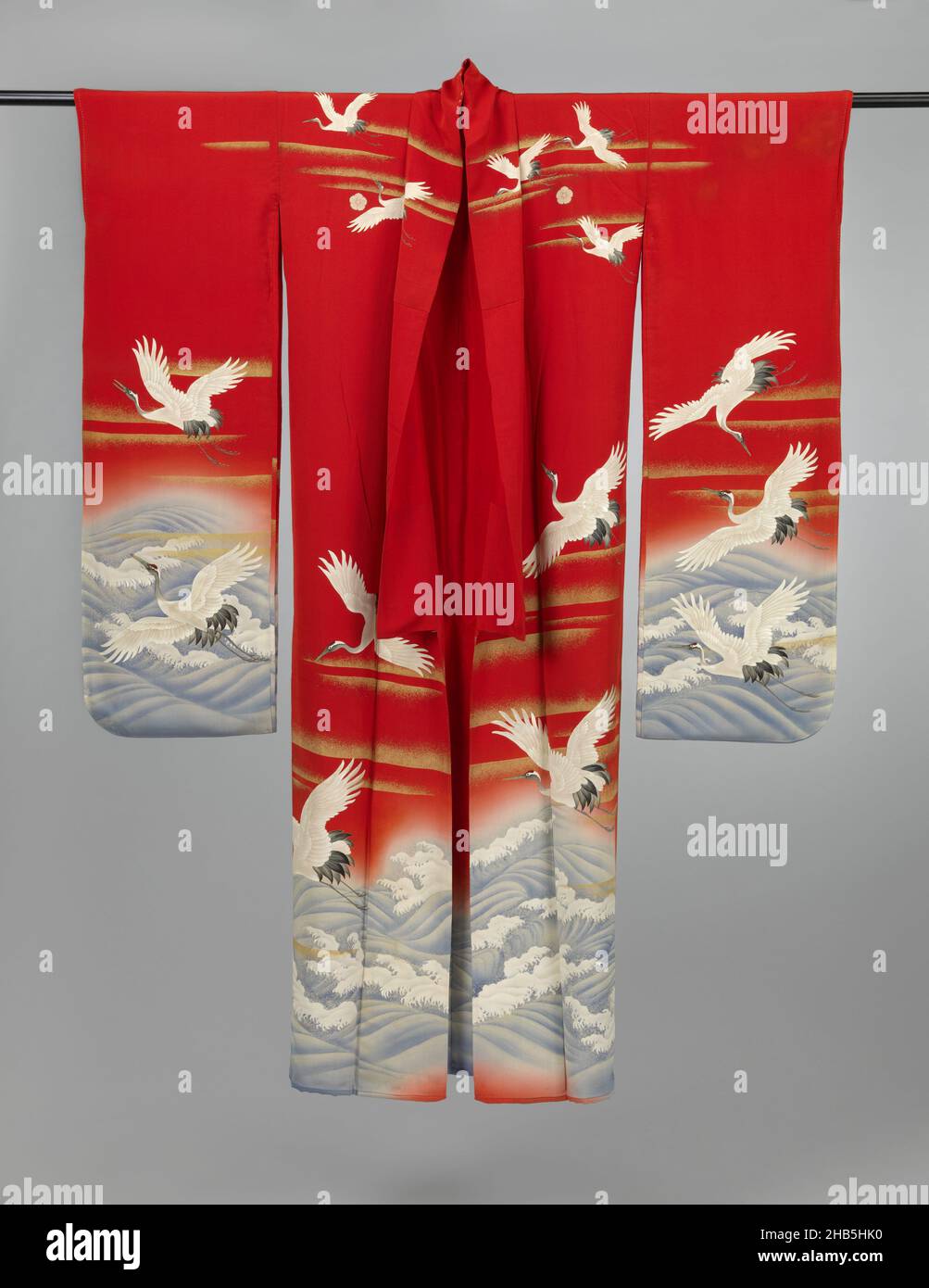 Kimono pour une femme non mariée, Furisode à Cranes au-dessus de la mer, le milieu (shitagi) d'un ensemble de trois kimono formel à manches longues pour une jeune femme non mariée (furisode), avec sur les manches, les panneaux avant et arrière une ornementation de grues au-dessus d'une mer agitée.Soie rouge crêpe (chirimen) avec décoration yuzen en blanc, noir et bleu, grues avec détails brodés, bandes nuageuses en feuille d'or et les vagues avec détails en fil d'argent et peinture blanche.Doublure en soie rouge.Cinq armes familiales (mon) d'œillets (nadeshiko)., fabricant: Anonyme, Japon, 1920 - 1940, soie,peinture, broderie Banque D'Images
