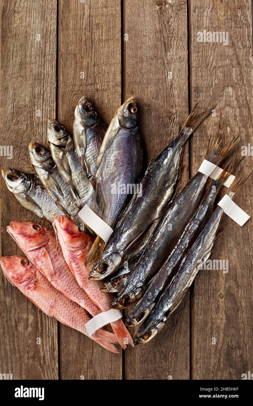 Torches salées séchées, sabrefrish et mulets rouges avec des étiquettes sur les queues sur fond de bois Banque D'Images