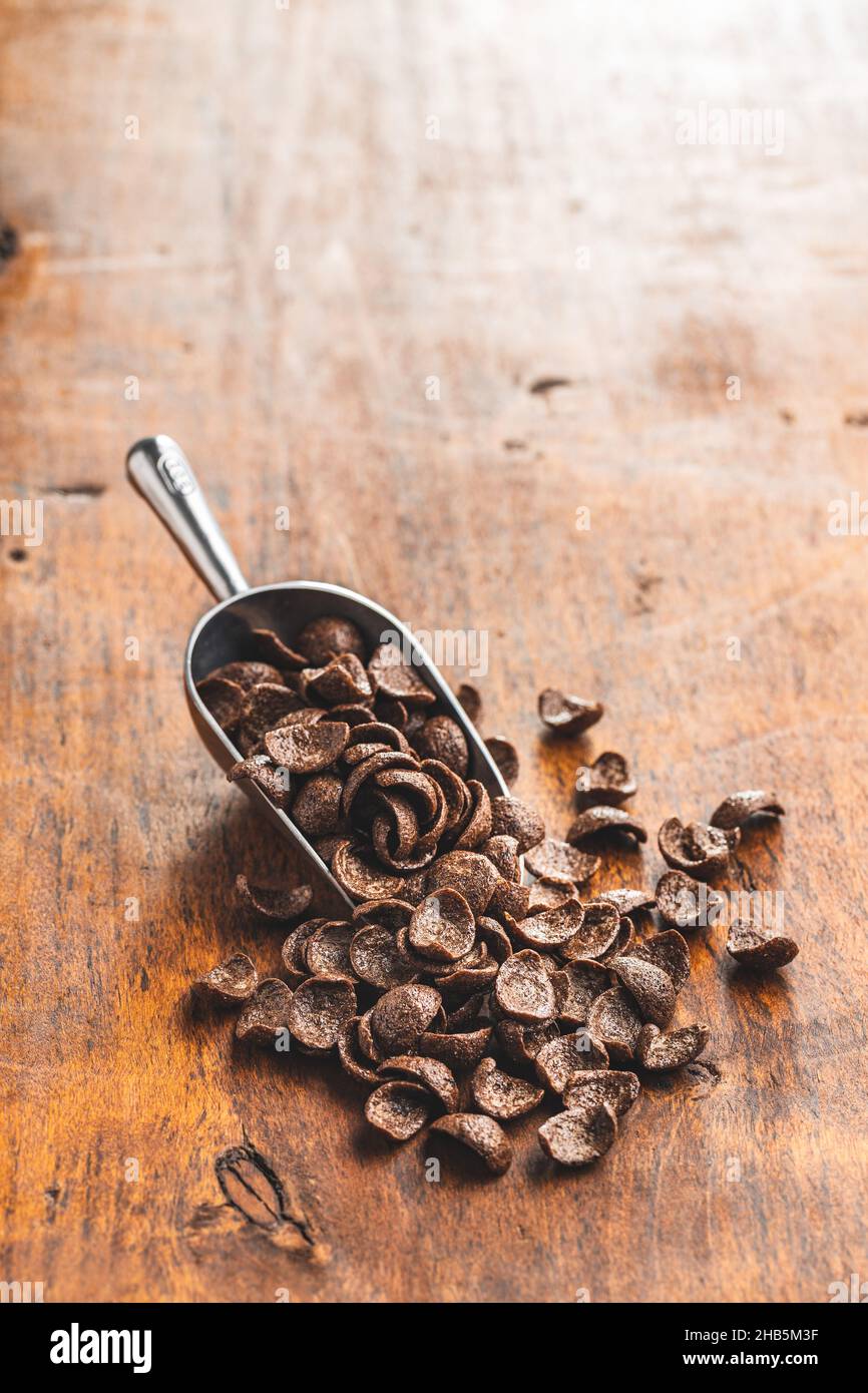 Petit-déjeuner au chocolat sucré, flocons de céréales dans une cuillère sur une table en bois. Banque D'Images