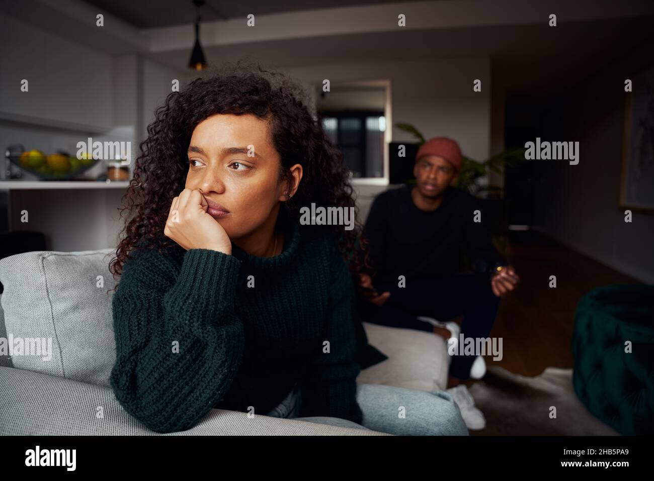Femme multiculturelle ignorant le copain noir tout en luttant sur le canapé dans un appartement moderne Banque D'Images