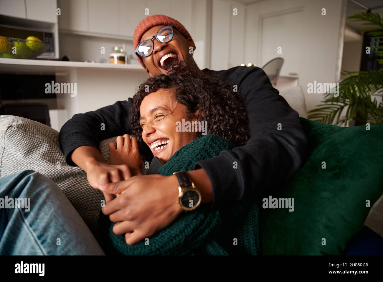 Un couple multiethnique tendance, assis sur un canapé, rit hystériquement.Photo de haute qualité Banque D'Images