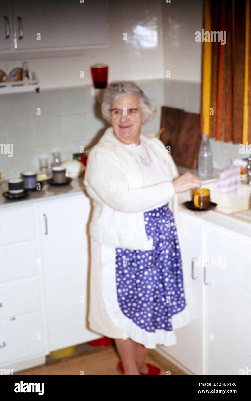 Femme âgée qui fait du thé à l'évier de cuisine à la maison des années 1970 Mode de vie britannique Banque D'Images