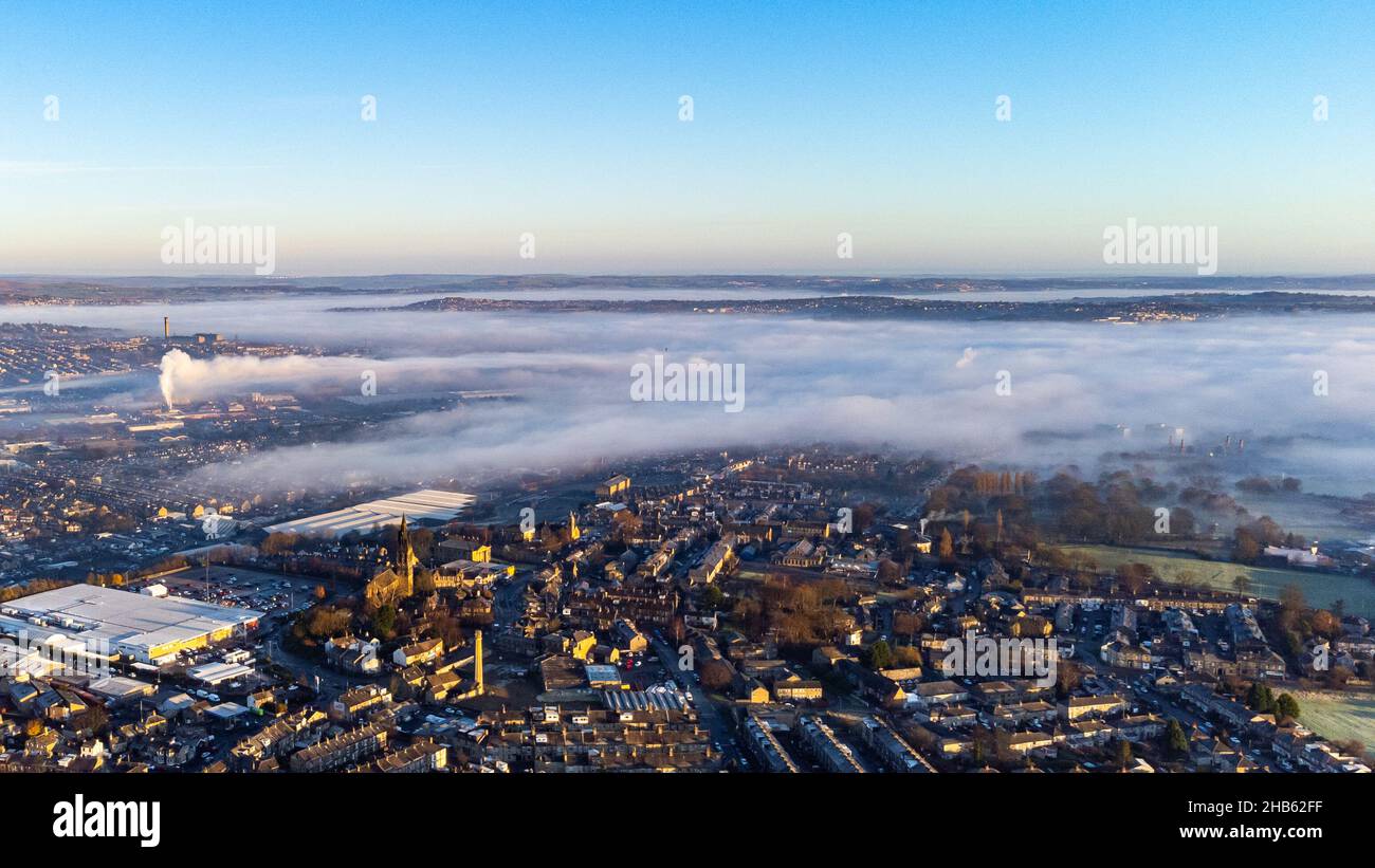 Bradford, West Yorkshire, Royaume-Uni. 17 décembre 2021. Inversion des nuages au-dessus de la ville par un matin frais d'hiver, regardant vers le nord-est. Une couche de nuages bas et de brouillard couvre une grande partie de la zone urbaine tandis que les structures plus hautes et le sol plus élevé restent visibles au-dessus de l'inversion. La photographie a été prise à partir d'une position élevée dans des conditions claires au-dessus de la couche de brouillard. Événement typique d'inversion de température hivernale enregistré dans cette ville du nord de l'Angleterre. Aucune personne ou aucun point de repère spécifique n'est l'objectif principal ; l'image montre l'effet météorologique à travers l'environnement bâti. Banque D'Images