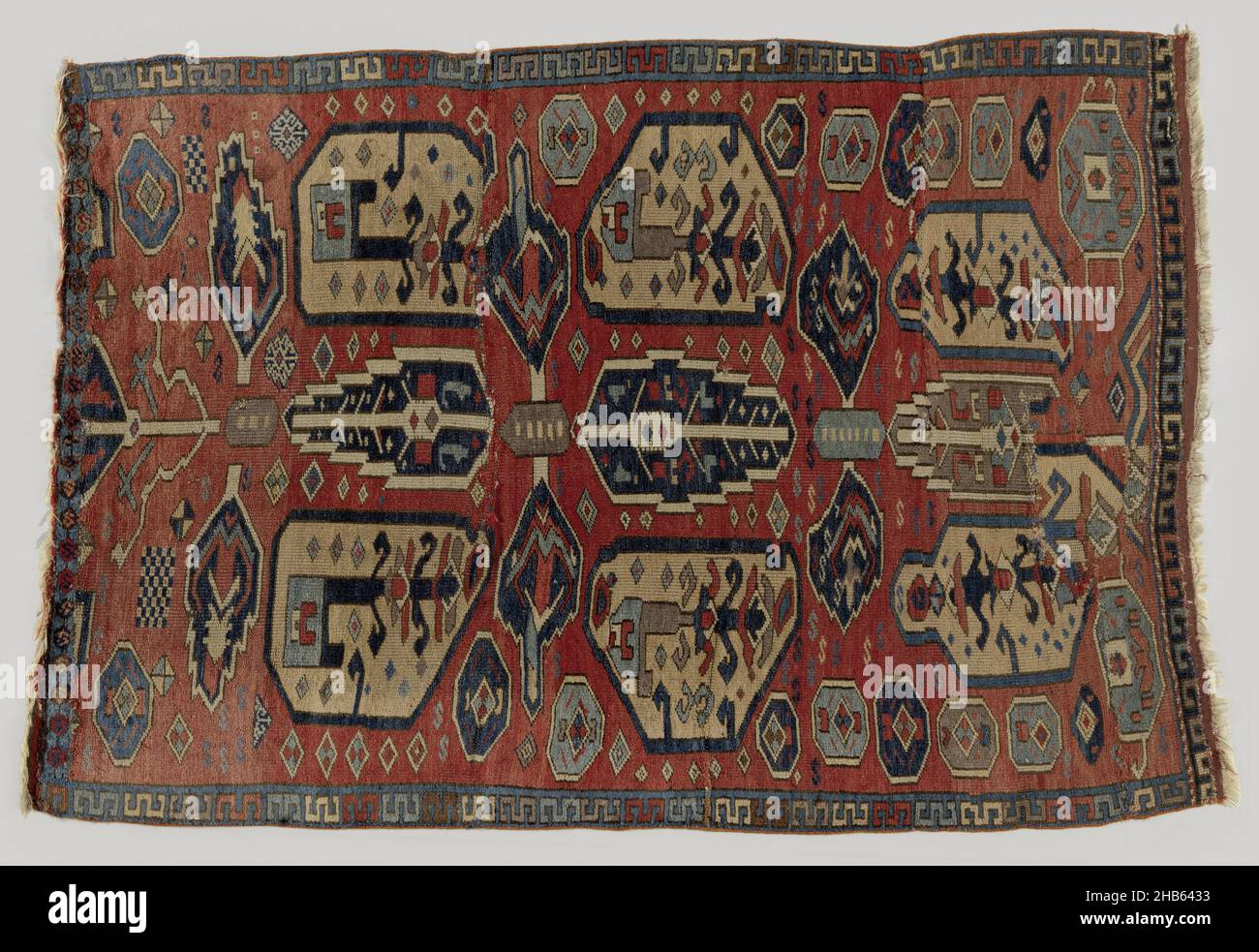 Robe avec décoration d'arbre, de fleur ou de feuille, robe avec décoration d'arbre, de fleur ou de feuille.Tapis nomade ?Champ central: Un champ rouge brique a une tige transversale pleine hauteur à laquelle les arbres de cyprès ou les feuilles sont abaissés vers le haut et vers le bas; un de gris et deux de bleu.Trois paires de petites feuilles de ditto en bleu.Cette tige est flanquée de grands motifs de fleur ou de poire en jaune maïs, avec des sommets cintrés.À l'intérieur se trouvent des branches rigides.Les contours des motifs sont épais et en blanc et bleu foncé respectivement.En outre, arrosés sur le champ de a.O. octadons.Bordure : seule une bordure intérieure présente, de bleu avec Banque D'Images