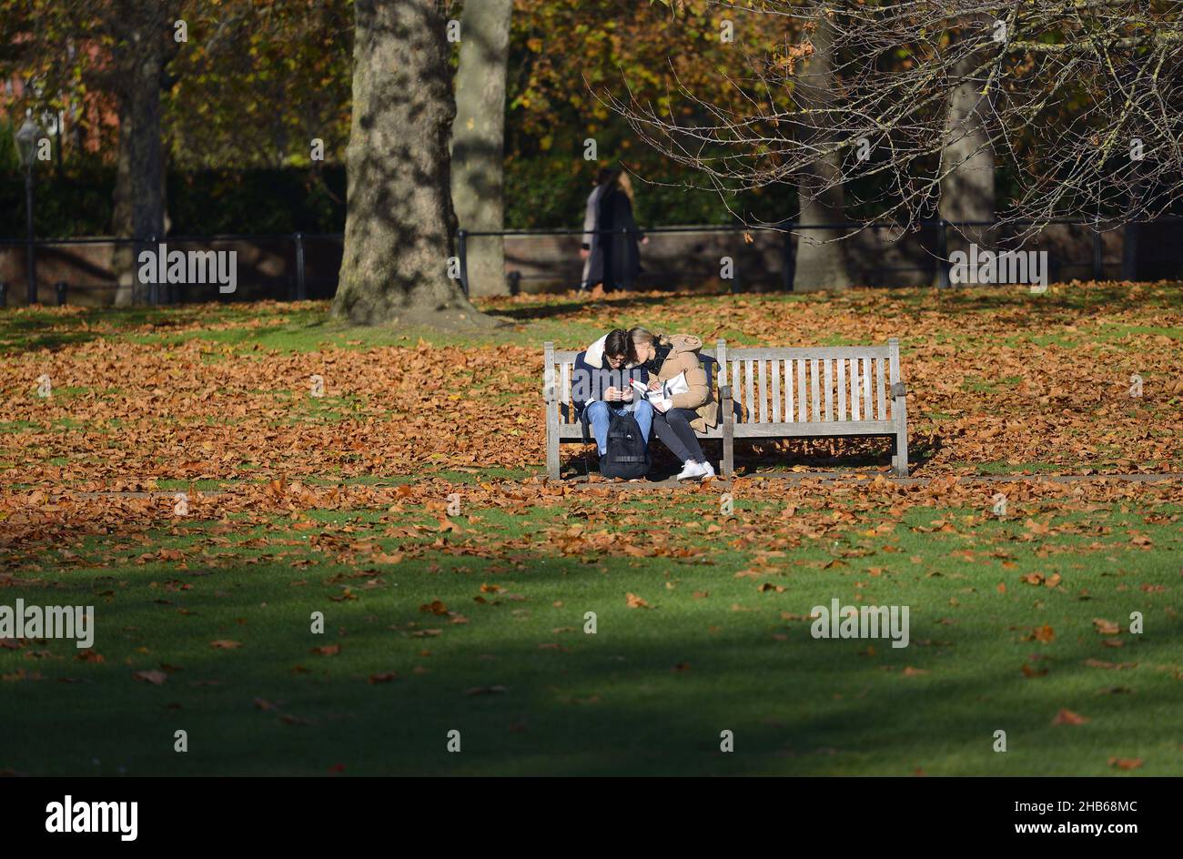 Londres, Angleterre, Royaume-Uni.Jeune couple sur un banc de parc à St James's Park, décembre 2021 Banque D'Images