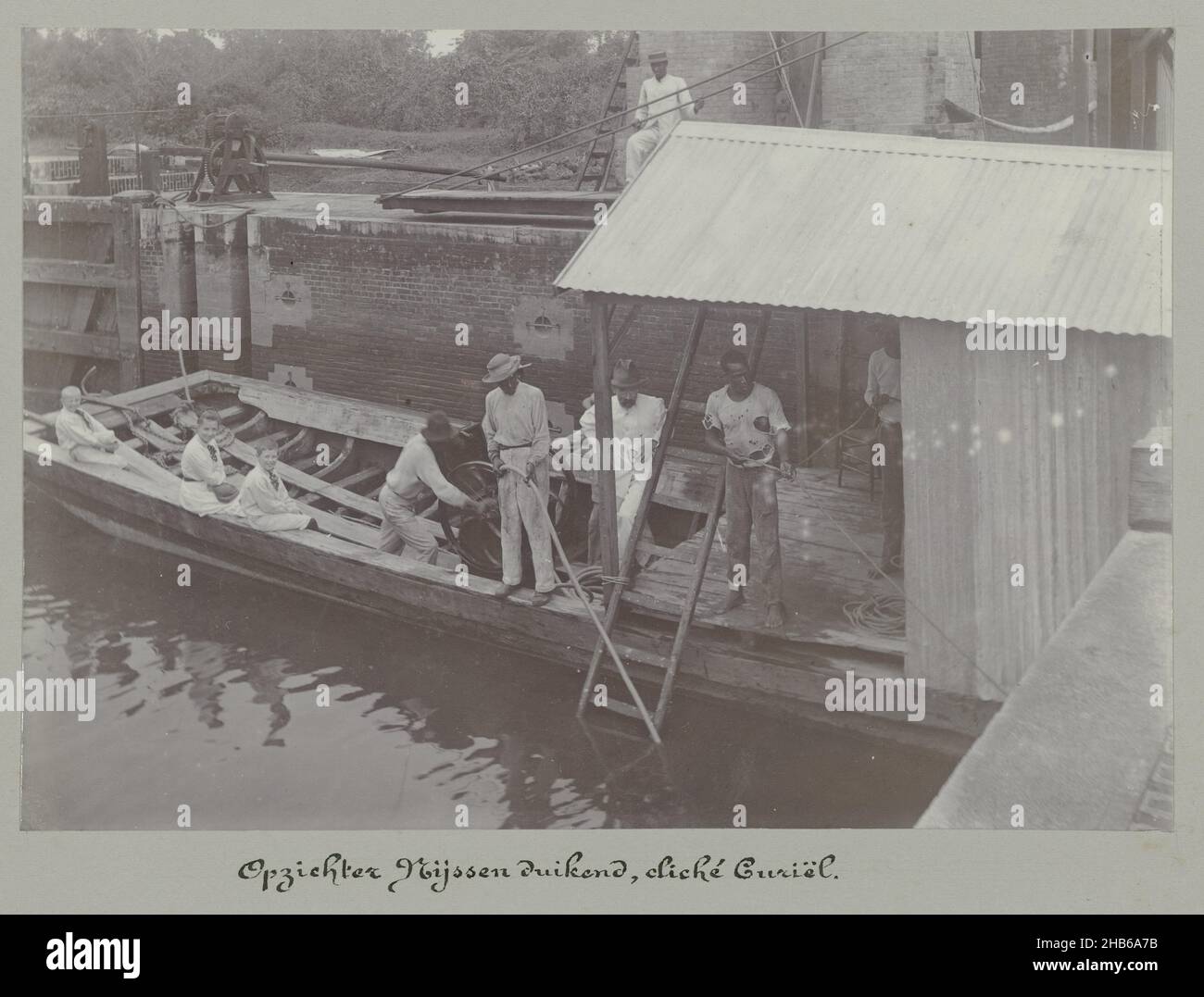 Overseer Nijssen plongée (titre sur objet), Un bateau de travail dans l'eau pendant les travaux à l'écluse de Havelaar près de Beekhuizen.Dans le bateau sont trois enfants européens qui regardent Overseer Nijssen travailler sous l'eau.Partie de l'album photo souvenir de Voyage (partie 3), sur la vie de la famille Dooyer dans et autour de la plantation Ma Retraite au Suriname dans les années 1906-1913., Augusta Curiel, Suriname, 1900 - 1913, support photographique,hauteur 118 mm × largeur 170 mm Banque D'Images