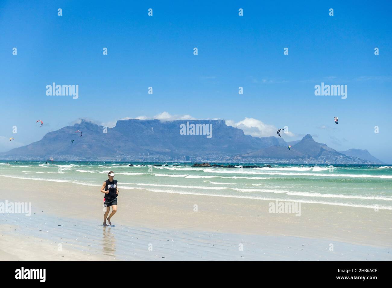 Jogger sur la plage du Cap, Afrique du Sud, avec Table Mountain en arrière-plan Banque D'Images