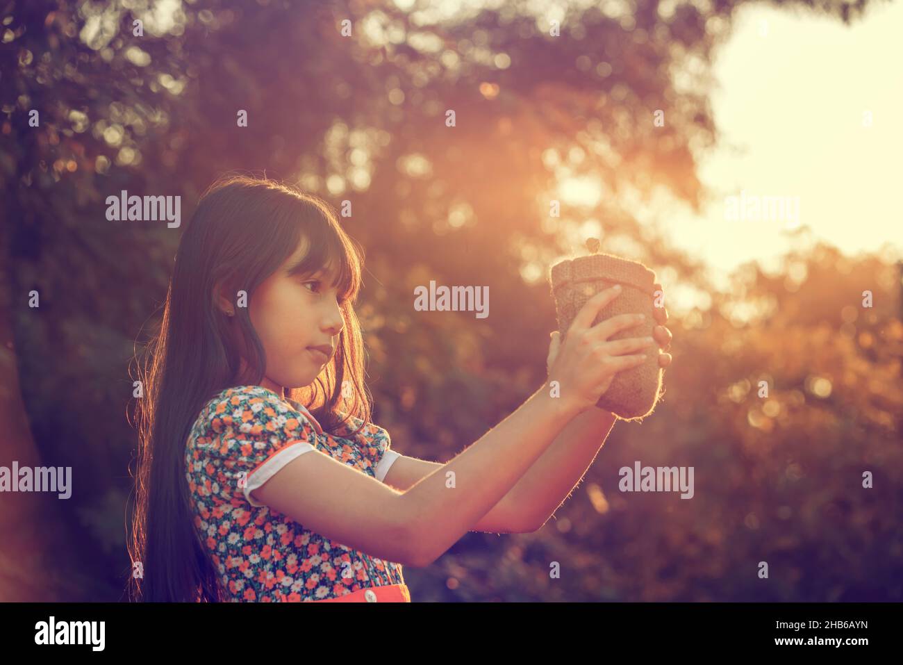 Jeune plante et fille.Petite fille mignonne donner une petite plante au soleil.Bonheur la nouvelle vie sauve la terre et le concept d'écosystème. Banque D'Images