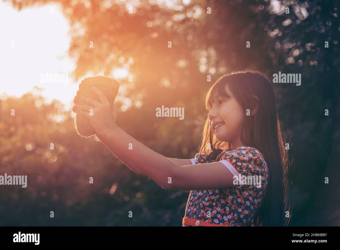 Jeune plante et fille.Petite fille mignonne donner une petite plante au soleil.Bonheur la nouvelle vie sauve la terre et le concept d'écosystème. Banque D'Images