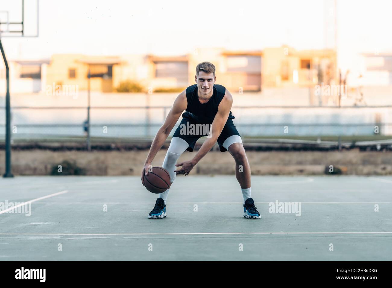 Un joueur de basket-ball rebondit le ballon sur un terrain extérieur Banque D'Images