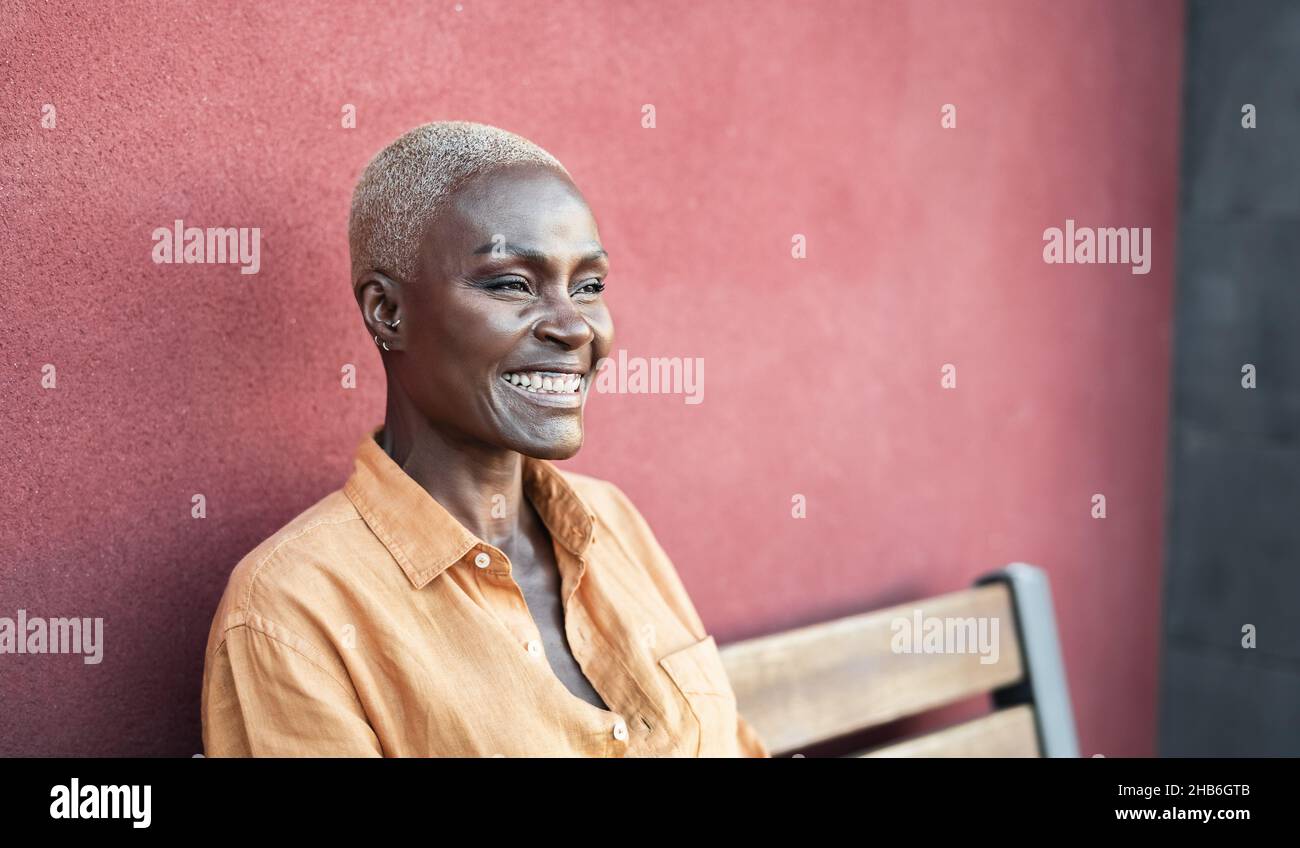 Portrait femme africaine senior souriant assis sur un banc à l'extérieur Banque D'Images