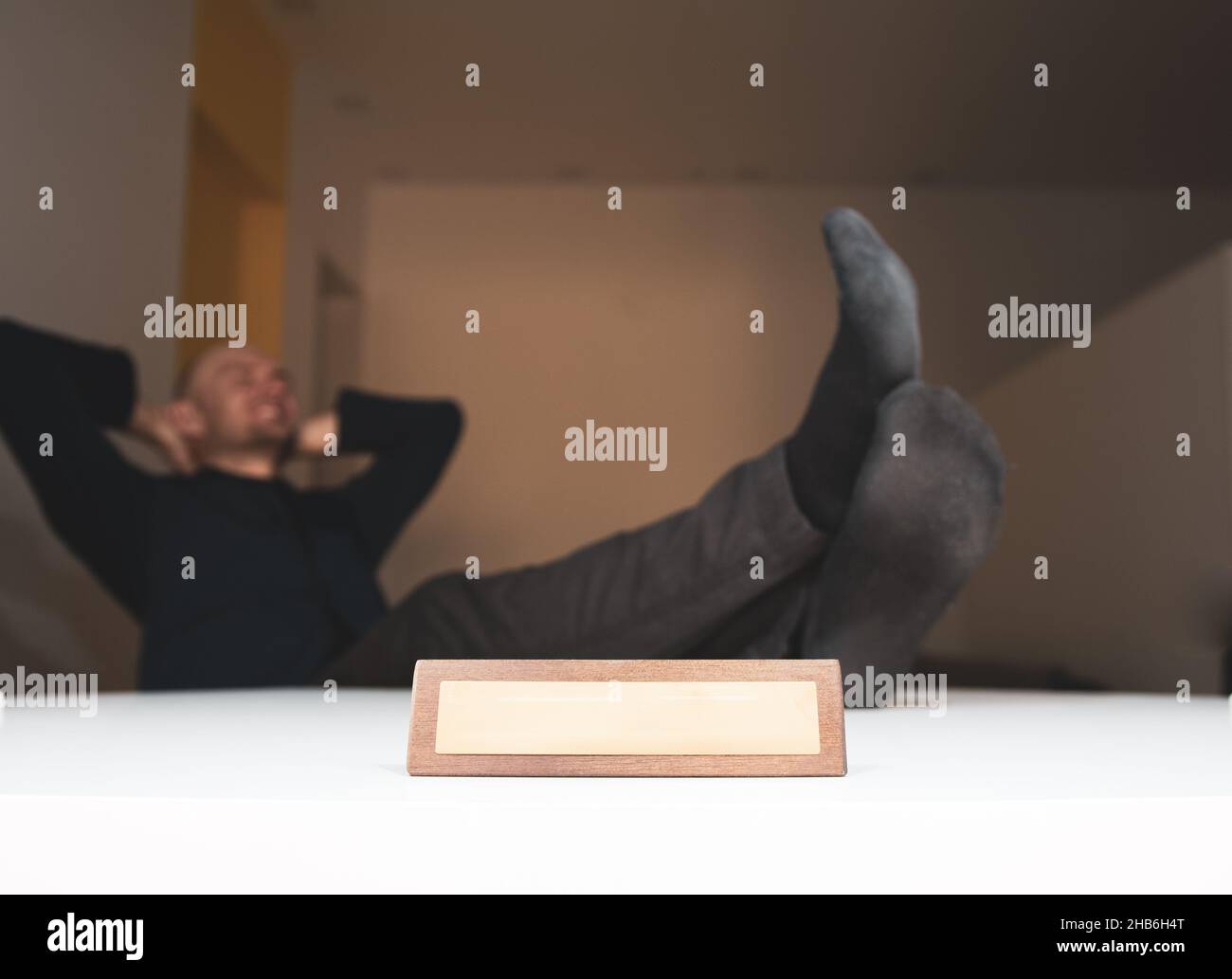 Personne sans chaussures et félets sur la table est détendu à la maison dans un salon avec une plaque de bureau en bois et espace de titre vierge.Travail fr Banque D'Images