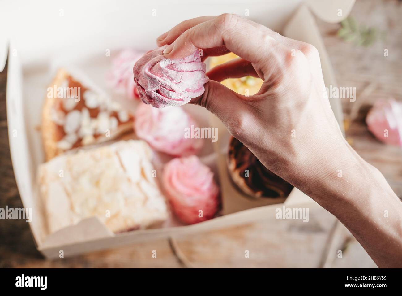 guimauves aux baies roses dans les mains, sur le fond des gâteaux dans une boîte.Guimauve souple et élastique à faire soi-même Banque D'Images