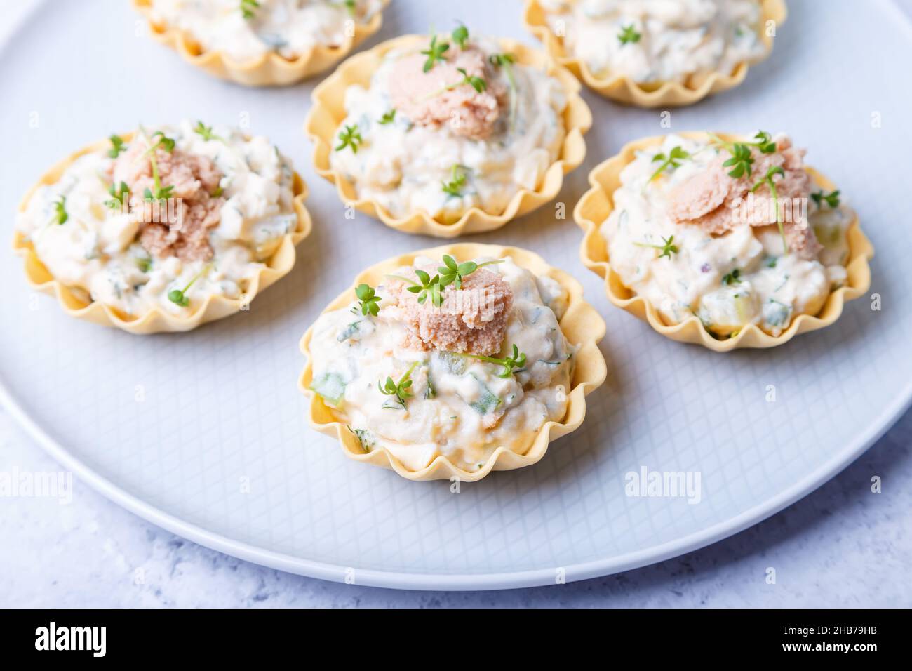 Tartelettes farcies au foie de morue, au caviar de morue, au concombre et aux microverts. Hors-d'œuvre traditionnel en portions froides dans un panier à pâtisseries. Gros plan, haut Banque D'Images