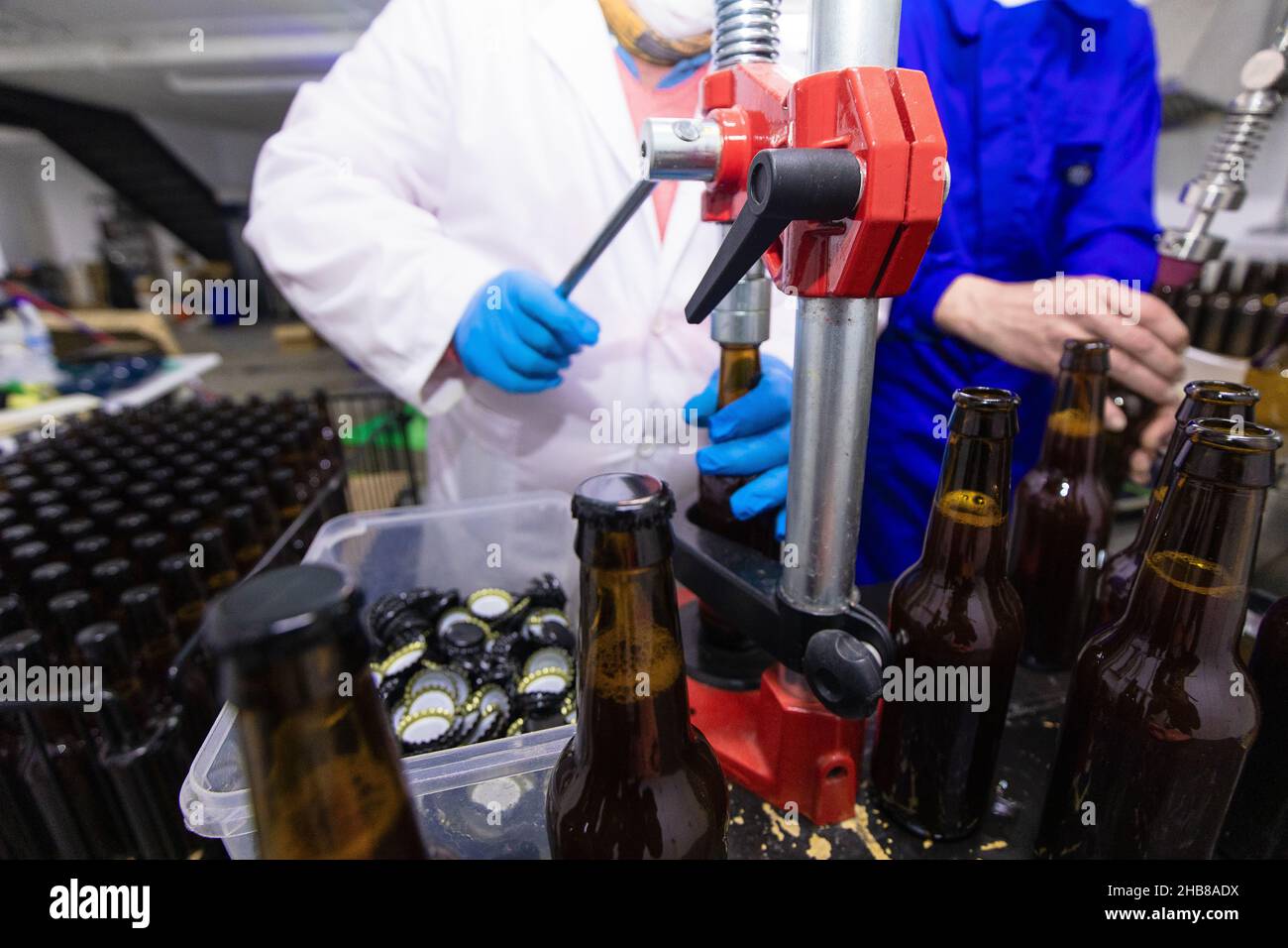 Employé qui ferme une bouteille de bière avec un bouchon pendant qu'il travaille à l'usine de production de bière Banque D'Images