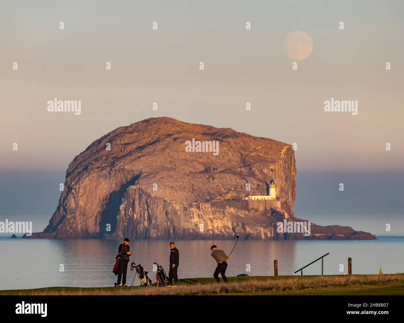 North Berwick, East Lothian, Écosse, Royaume-Uni, 17th décembre 2021.Météo au Royaume-Uni : la pleine lune s'élève au-dessus de Bass Rock.La pleine lune de décembre s'appelle la « Lune froide ».Aujourd'hui, il s'est levé juste avant le coucher du soleil.Photo : les golfeurs apprécient un dernier match avant que le soleil ne se couche sur le parcours de golf de Glen Banque D'Images