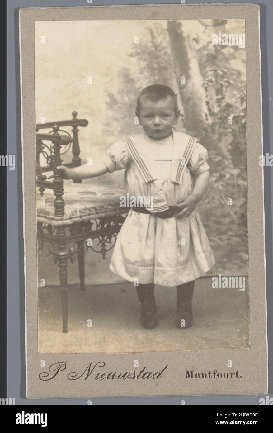 Portrait d'un enfant inconnu à côté d'une chaise, Pieter Jan Nieuwstad (mentionné sur l'objet), Montfoort, 1905 - 1910, papier baryta, carton,imprimé gélatine argent, hauteur 105 mm × largeur 64 mm Banque D'Images