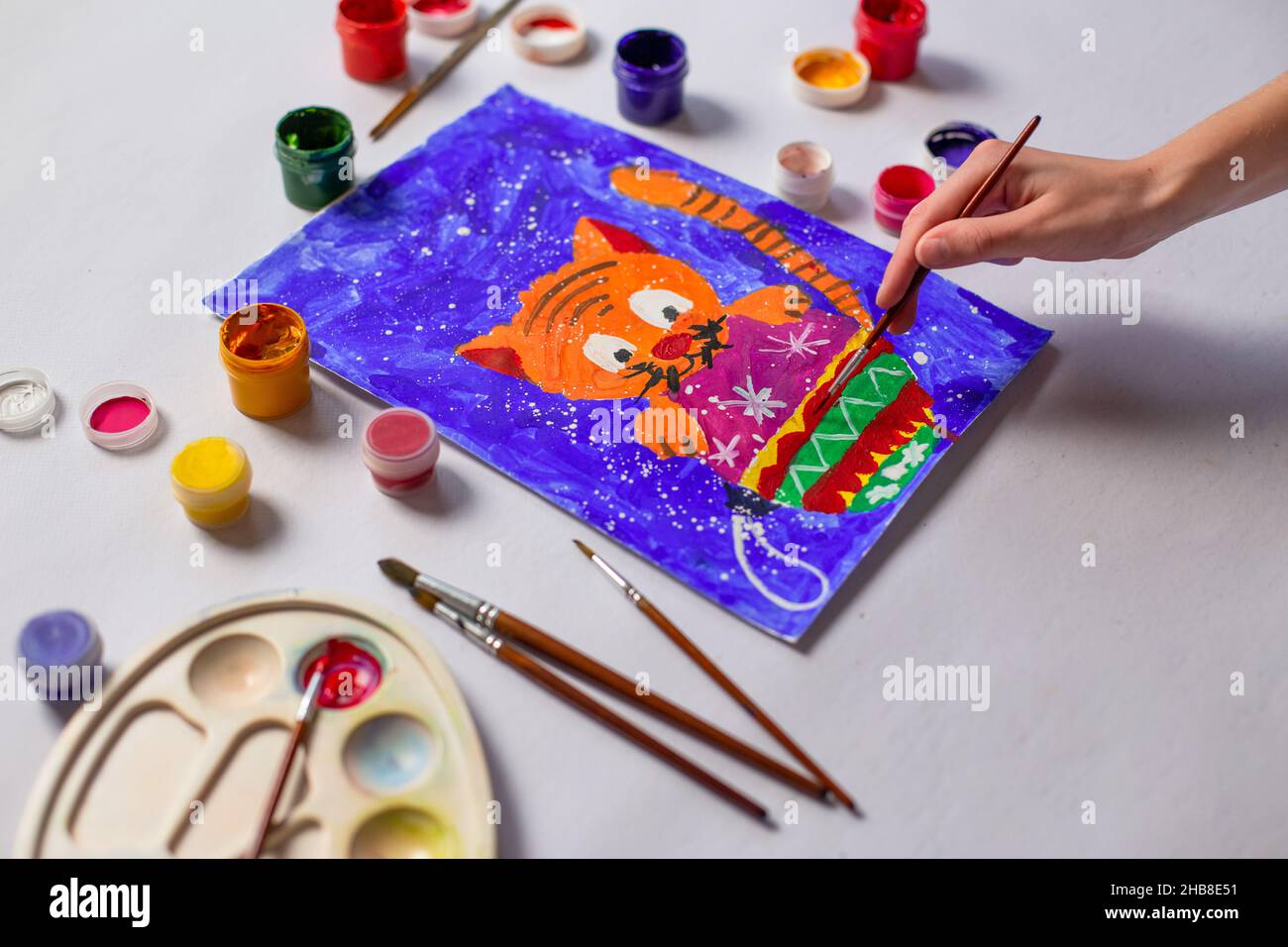 Un enfant peint un chat et un jouet d'arbre de Noël avec des peintures.Enfants noël dessin gros plan Banque D'Images