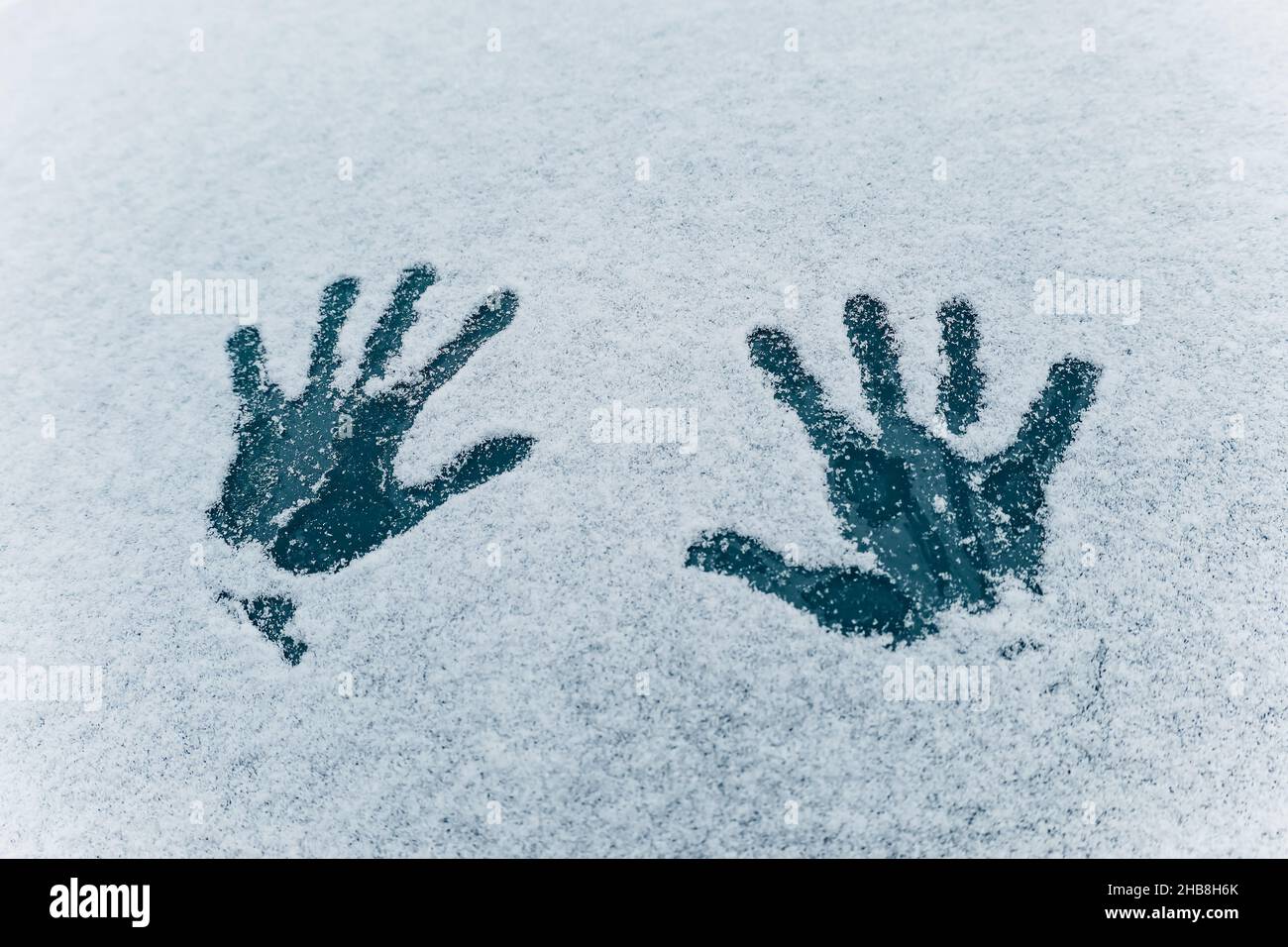Impression de deux mains de paume sur la texture blanche de la neige.Deux empreintes humaines sur fond de verre bleu foncé gelé.Concept de plaisir d'hiver et temps froid Banque D'Images