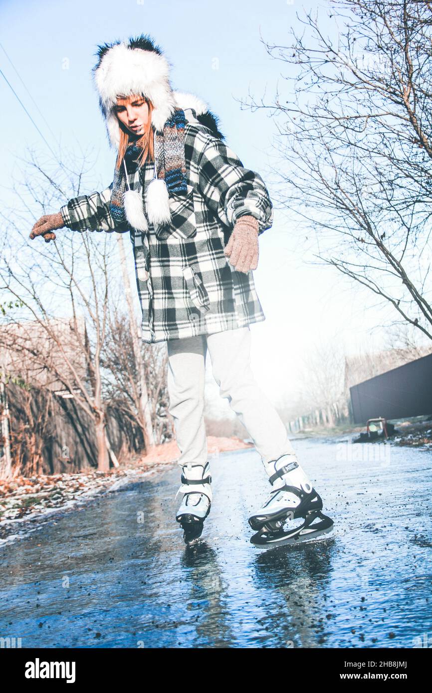 Fille patinage sur glace.Patinage artistique.Loisirs d'hiver.Glaçage hivernal de l'asphalte Banque D'Images