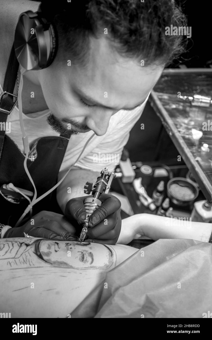 Le tatoueur professionnel démontre le processus d'obtenir le tatouage en studio de tatouage Banque D'Images