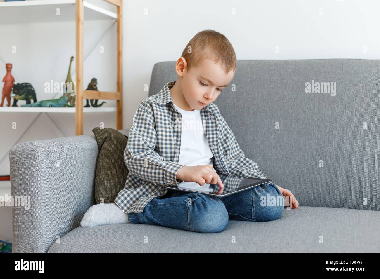 Garçon sans contrôle parental perdre du temps à jouer.Gamin s'amusant avec une tablette.Éducation de la petite enfance et loisirs d'âge élémentaire Banque D'Images