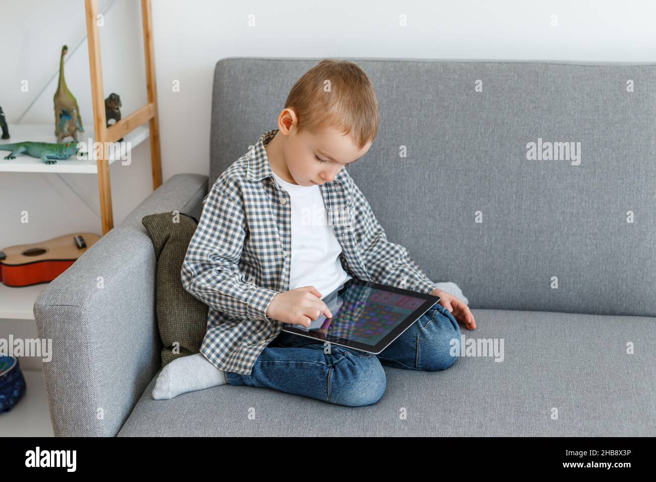 Garçon sans contrôle parental perdre du temps à jouer.Gamin s'amusant avec une tablette.Éducation de la petite enfance et loisirs d'âge élémentaire Banque D'Images