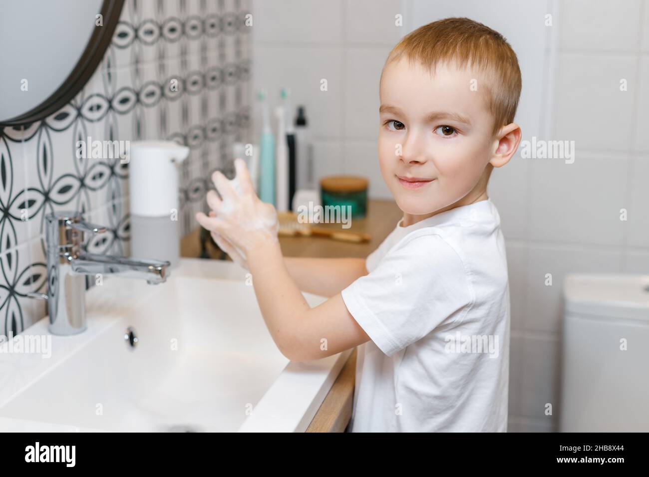 Un garçon se lavant les mains dans la salle de bains à l'aide d'un  distributeur de savon àHygiène des enfants, soins de santé et soins du corps  Photo Stock - Alamy