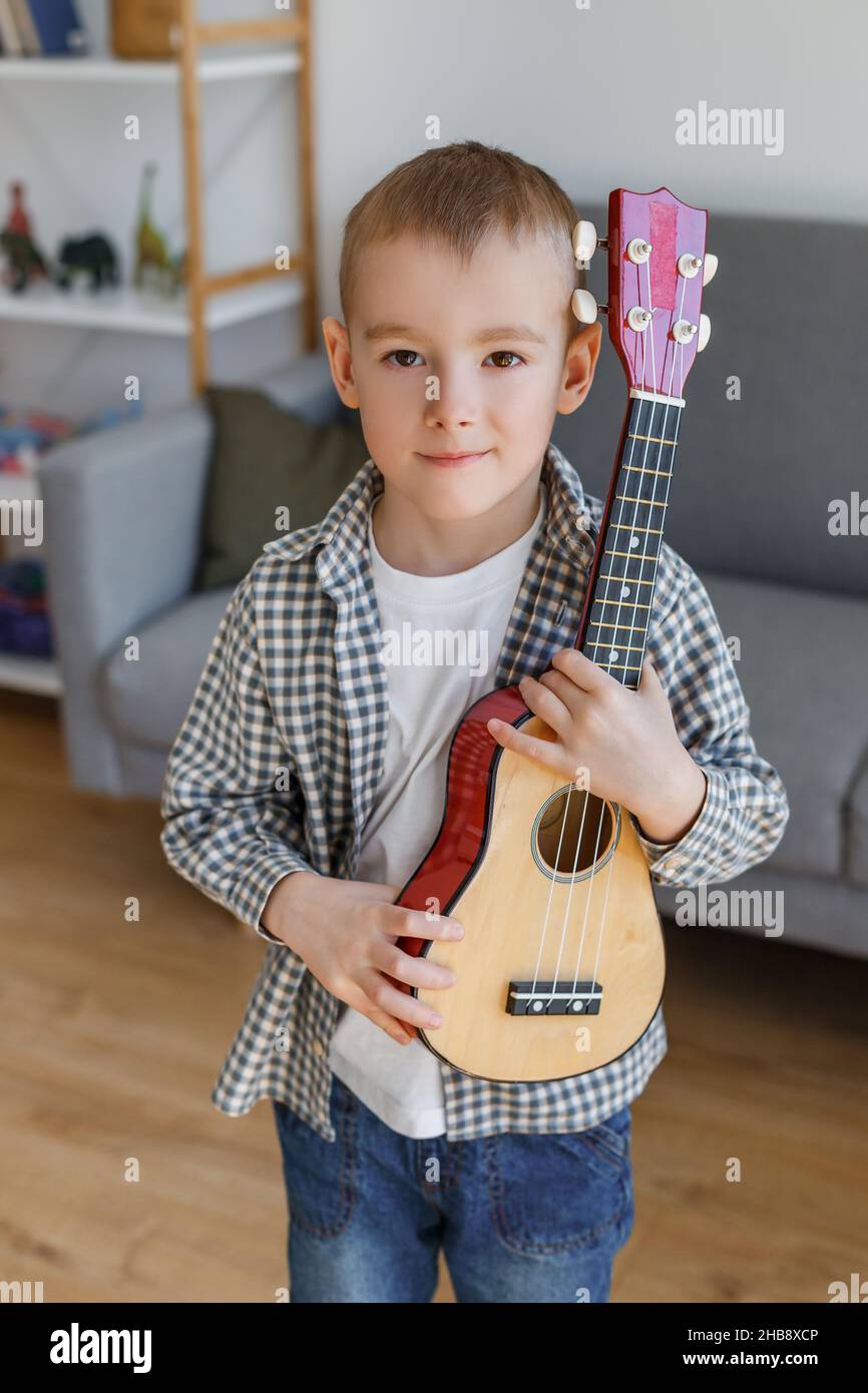 Un jeune talentueux tenant une soprano ukulele à la maison.Petit garçon d'âge préscolaire apprenant la guitare à loisir.Concept d'éducation de la petite enfance et de passe-temps musical Banque D'Images