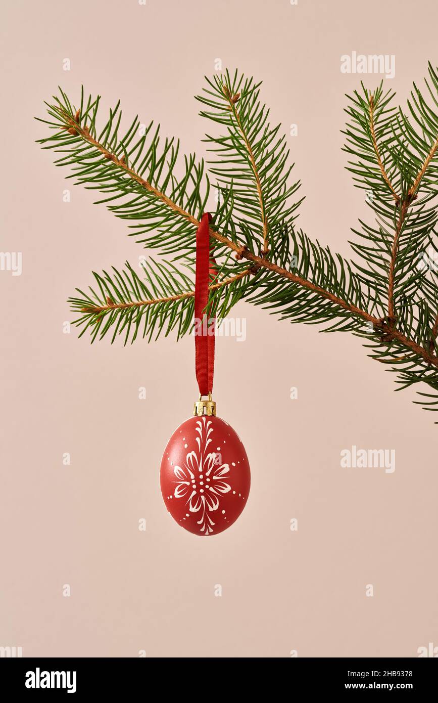Œuf de Pâques rouge décoré de cire accrochée à une branche d'un épicéa comme décoration de Noël Banque D'Images