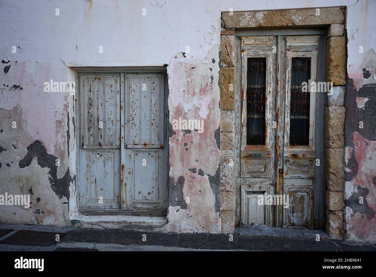 Ancienne façade de maison rurale abandonnée avec un mur en stuc et une porte et une fenêtre en bois gris à Koroni, Messinia Grèce. Banque D'Images