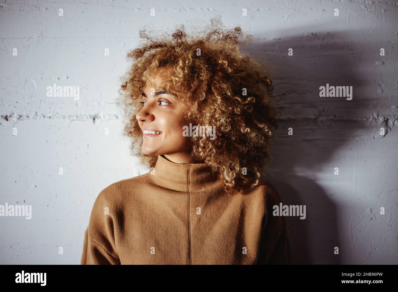 Profil de la race mixte souriante hip hop fille.La fille est debout contre le mur blanc. Banque D'Images