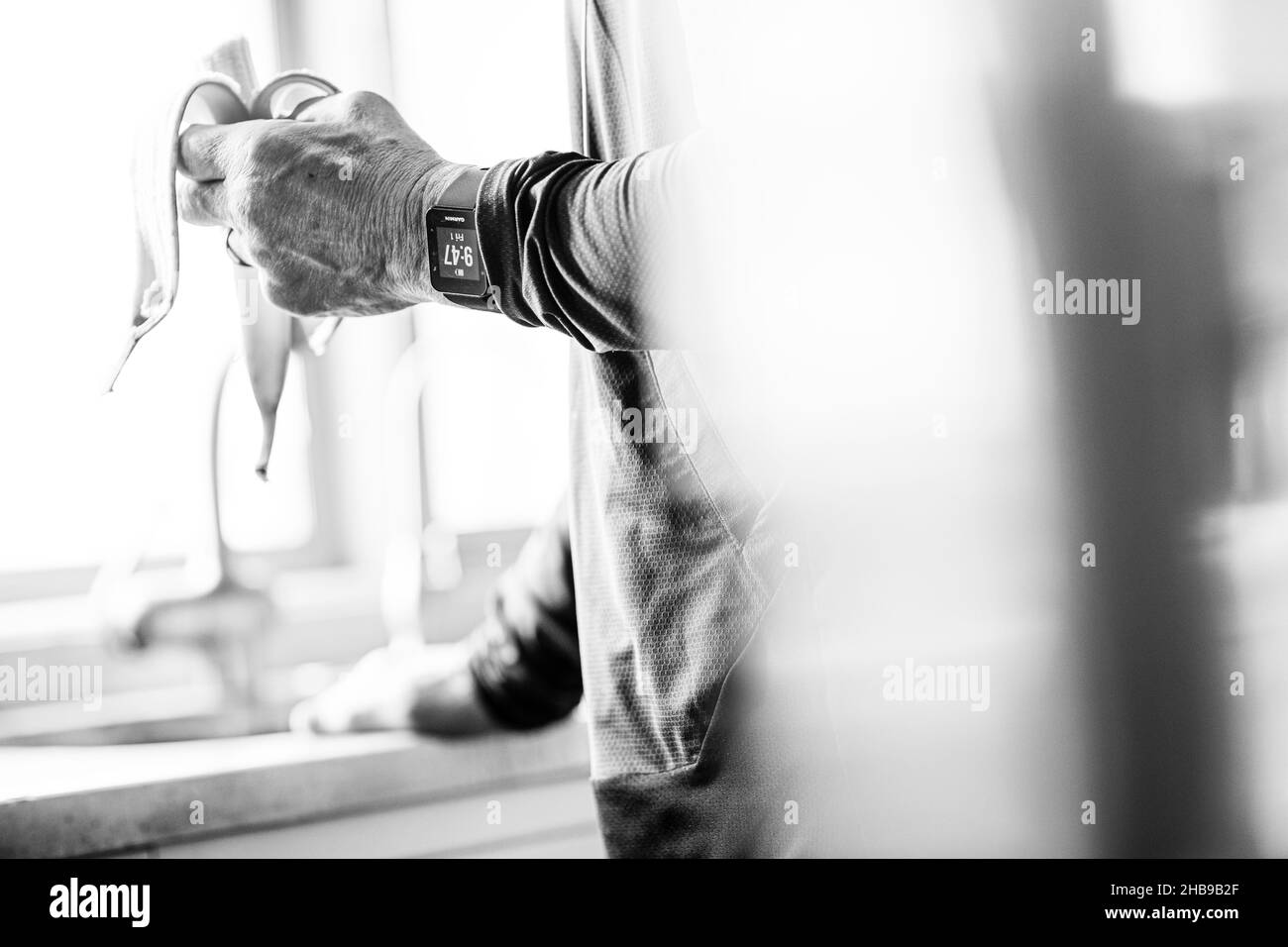 Homme âgé mangeant une banane dans sa cuisine après une course Banque D'Images