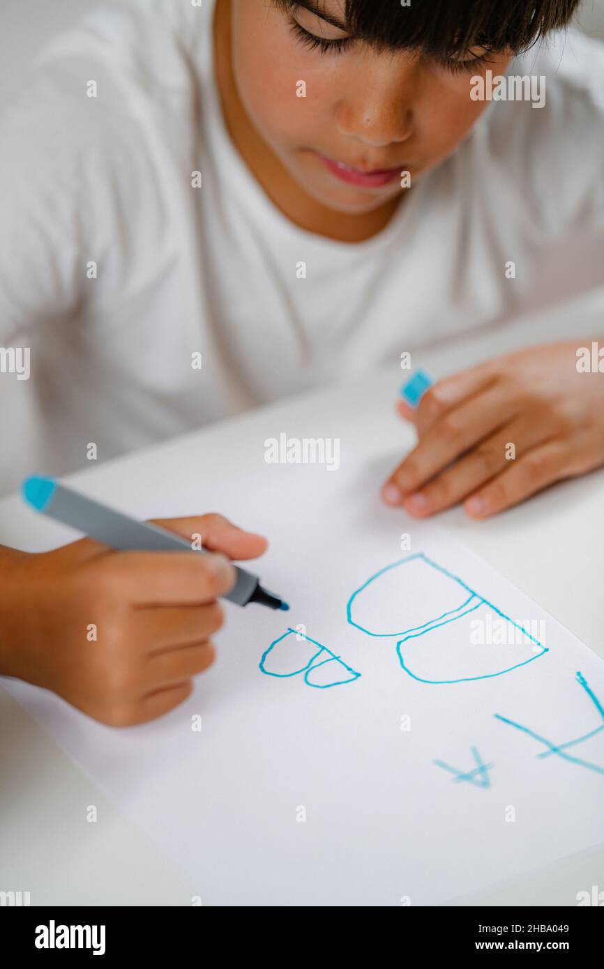 Garçon écrivant des lettres dans un test de dépistage préscolaire. Banque D'Images