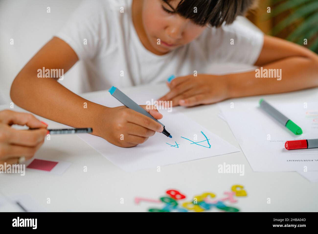 Garçon écrivant des lettres dans un test de dépistage préscolaire. Banque D'Images